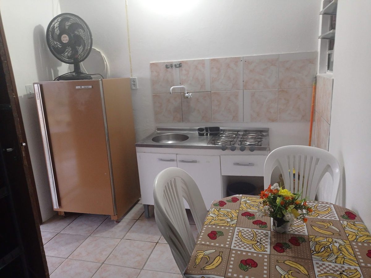 Cozinha de uma unidade com geladeira, fogão, pia e mesa com cadeiras